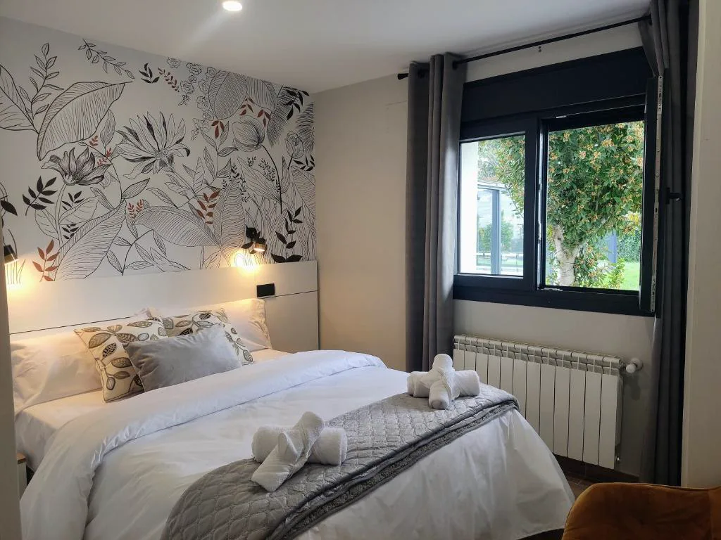 Dormitorio blanco con papel pintado de hojas y cortinas grises