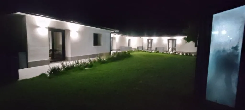 Casa iluminada de noche con jardín de césped