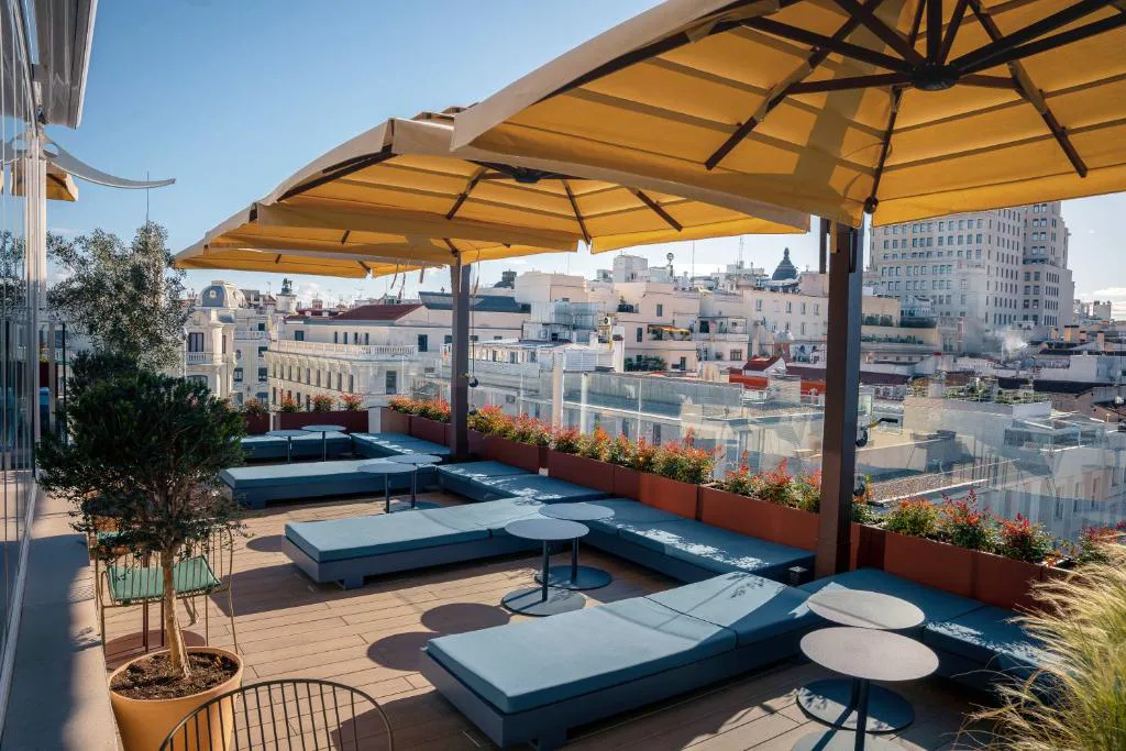 Terraza con sombrilla amarilla y tumbonas azules