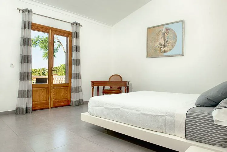 Dormitorio con puertas balconeras de madera y cortinas de rayas, Sa Figuera Roja