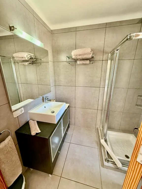 Baño moderno con ducha de mampara de vidrio y azulejos grises, Sa Figuera Roja
