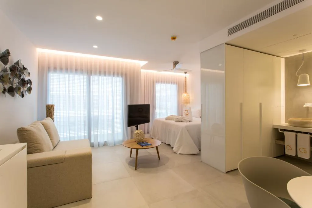 Suite con sofá beige, cama y baño integrado con bañera exenta, Sa Pedrera Suites & Spa