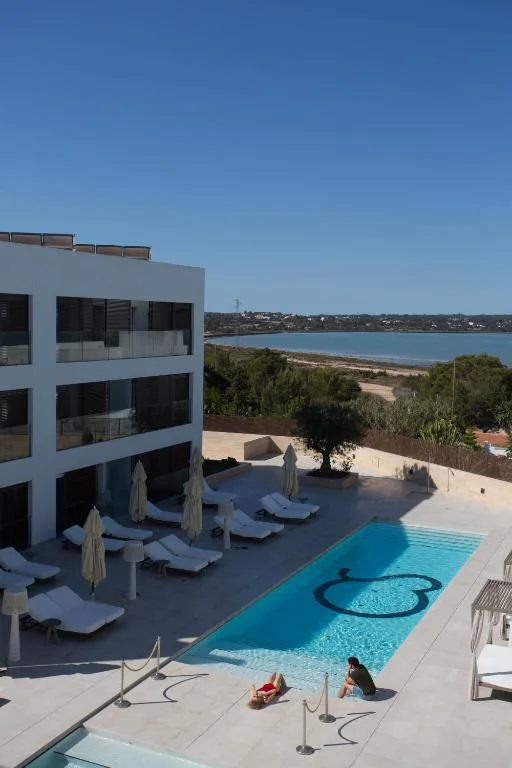 Piscina con tumbonas y vistas al Estany des Peix al fondo, Sa Pedrera Suites & Spa