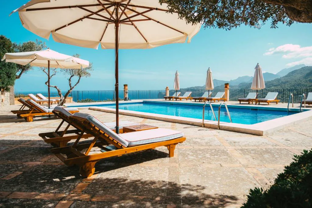 Piscina rectangular con tumbonas de madera y vistas al mar y la costa, Sa Pedrissa