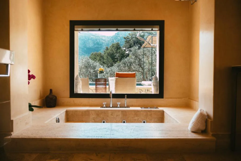 Bañera de piedra con vistas a la sierra a través de un gran ventanal, Sa Pedrissa