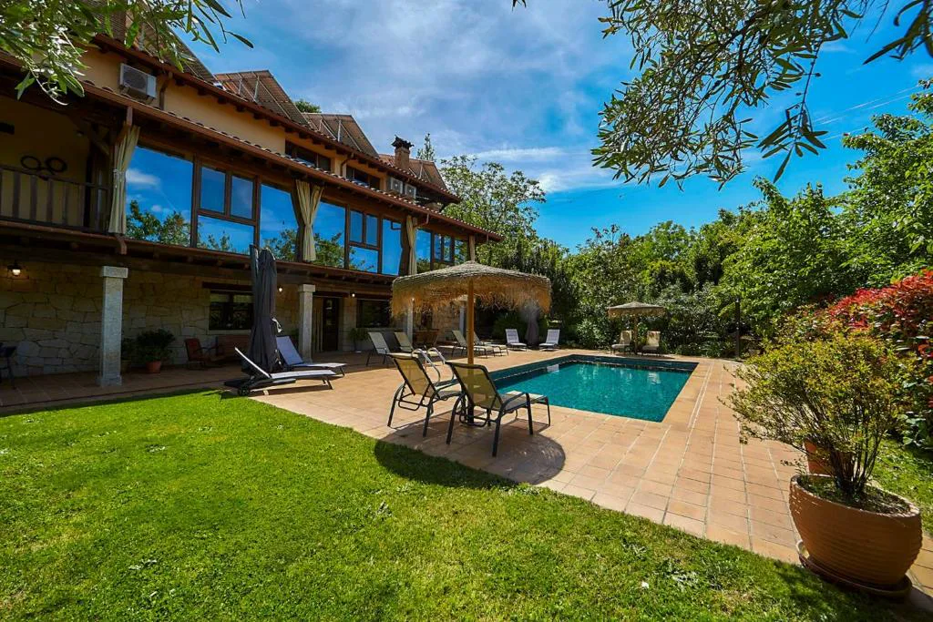 Hotel de madera con cristaleras, jardín y piscina al fondo
