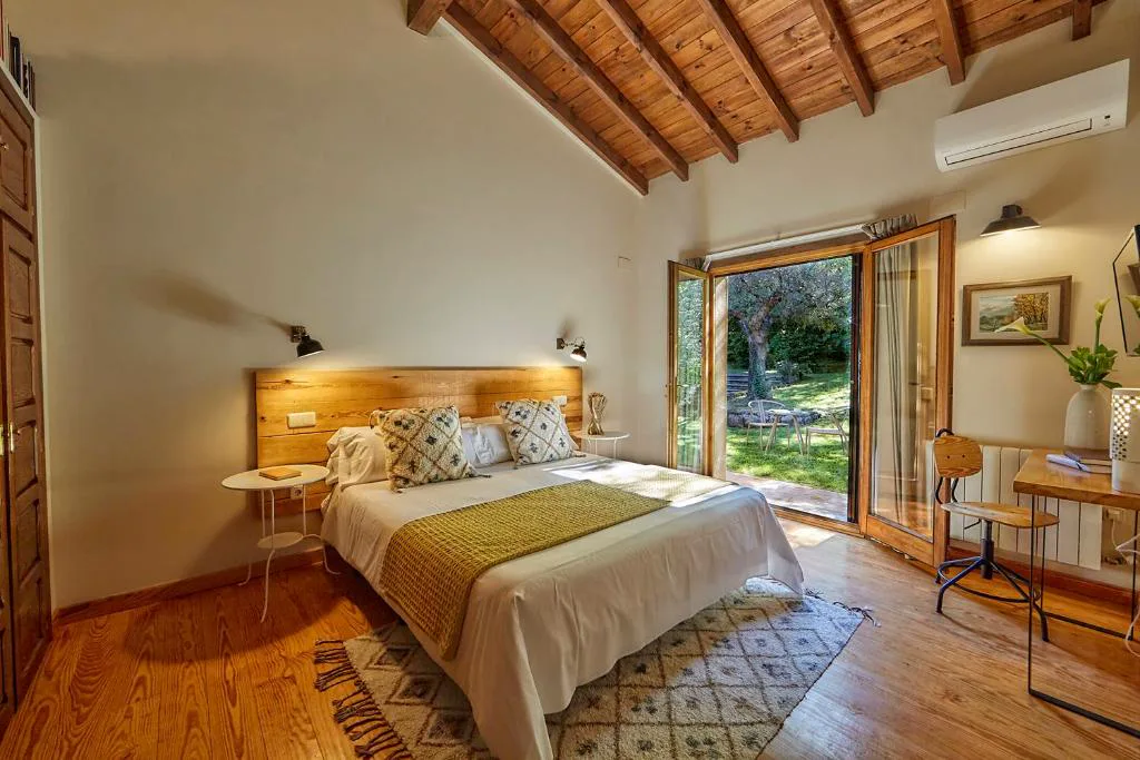 Habitación con cabecero de madera, alfombras y puerta al jardín