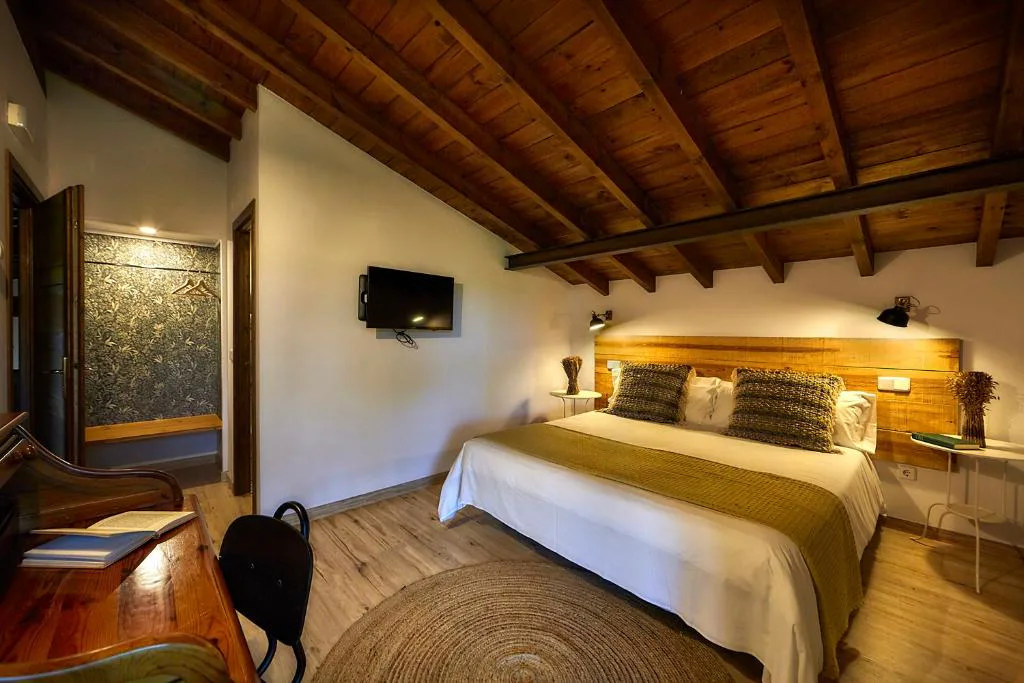 Habitación de vigas de madera con cama doble y escritorio