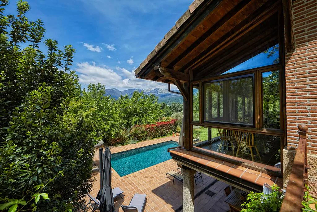 Cabaña de madera con cristales sobre la piscina y vistas al valle