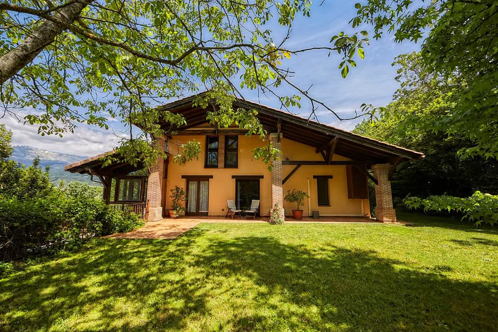 Casa de piedra y madera entre árboles y césped