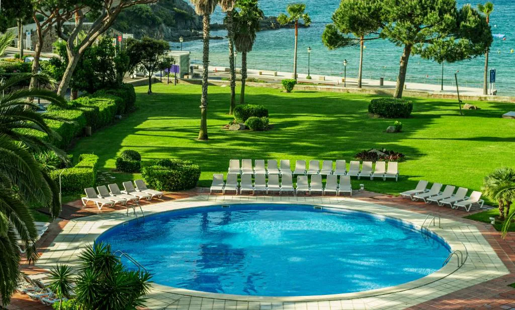 Piscina circular entre jardines con vistas al mar