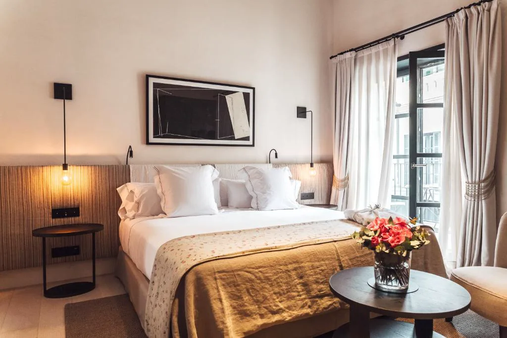 Dormitorio con ropa de cama en tonos mostaza y balcón con vistas al casco antiguo, Sant Francesc Hotel Singular