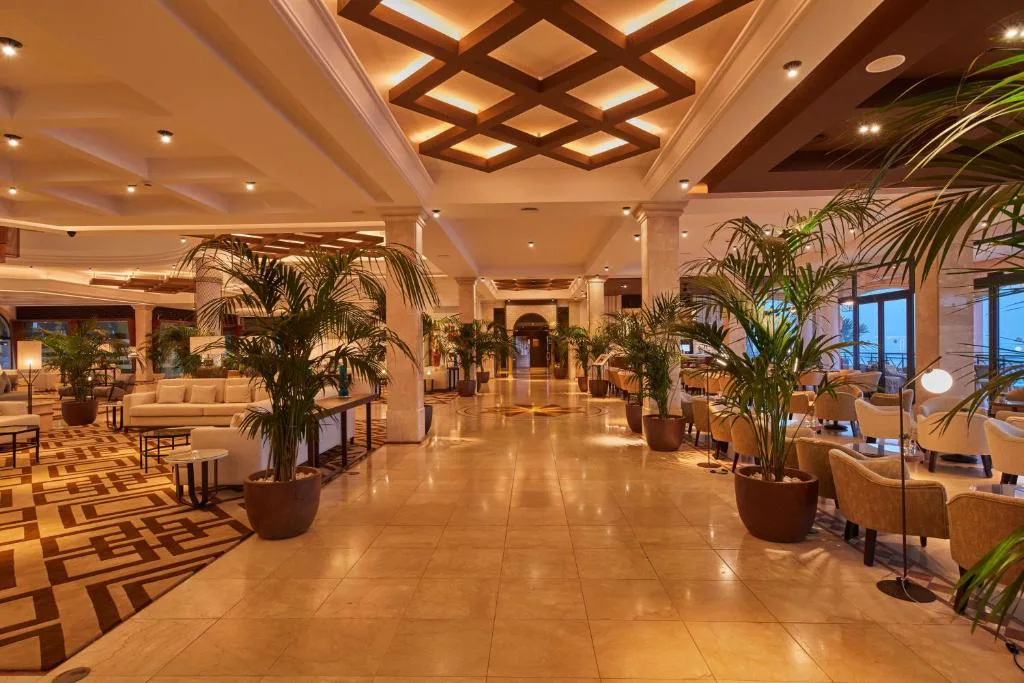 Lobby con techos de madera geométricos y palmeras interiores, Secrets Bahía Real