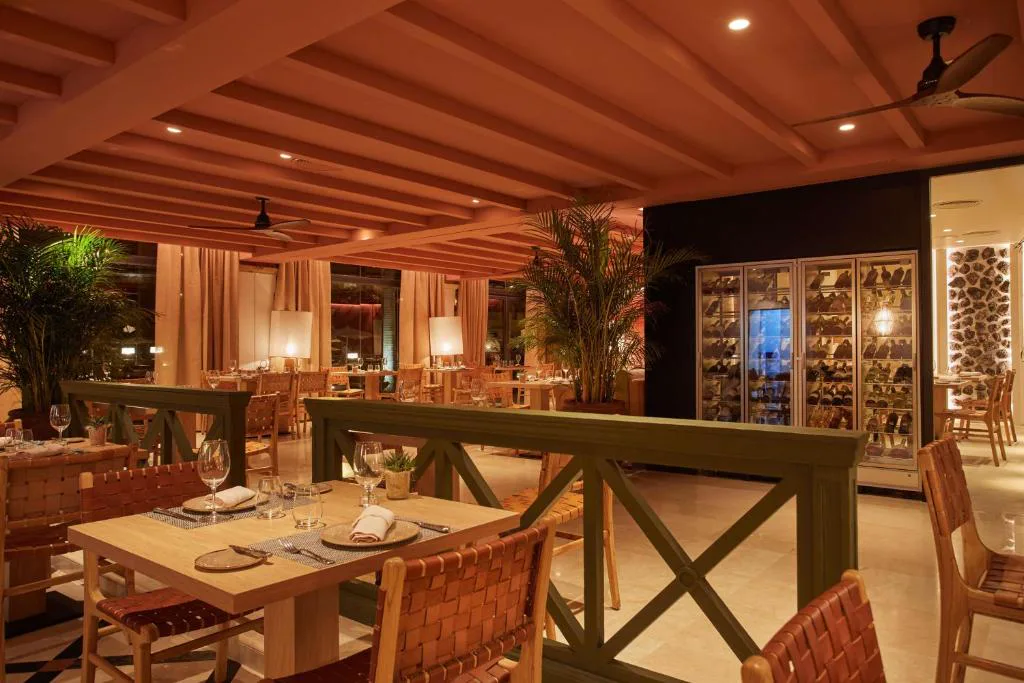Restaurante con bodega acristalada y mesas con mantelería de noche, Secrets Bahía Real