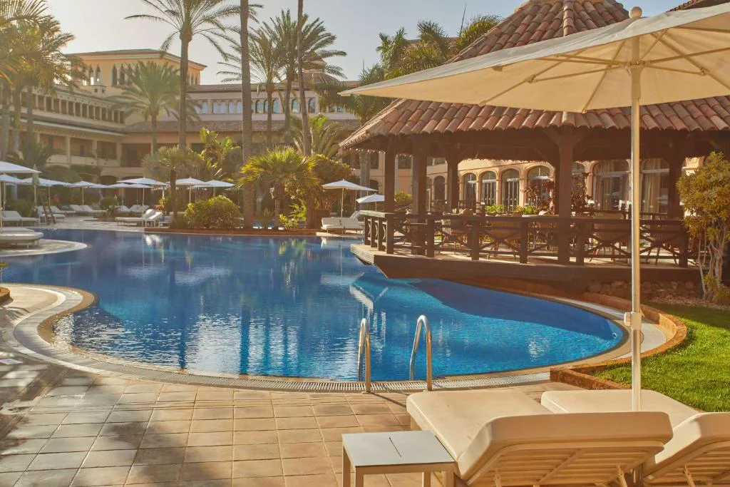 Piscina exterior junto a un cenador de madera con techo de teja, Secrets Bahía Real