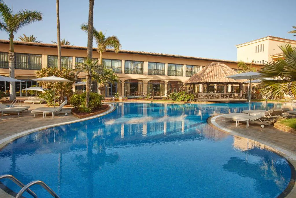 Piscina exterior curva con cenador de madera en Secrets Bahía Real Resort & Spa, Corralejo, Fuerteventura