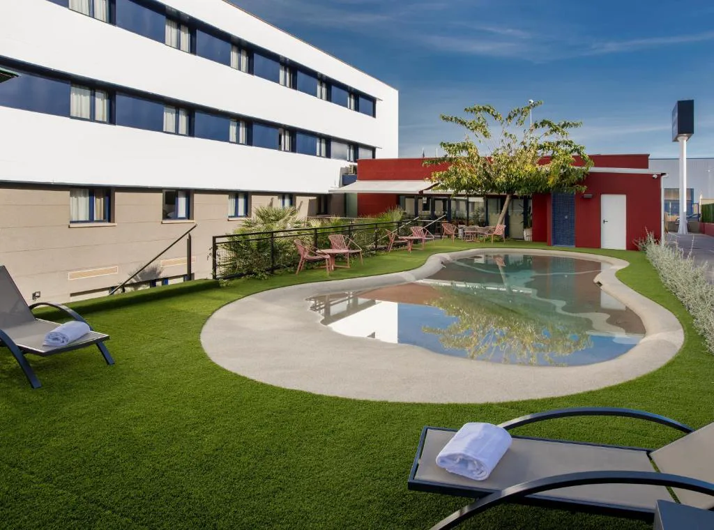 Piscina exterior con toldos y hotel al fondo