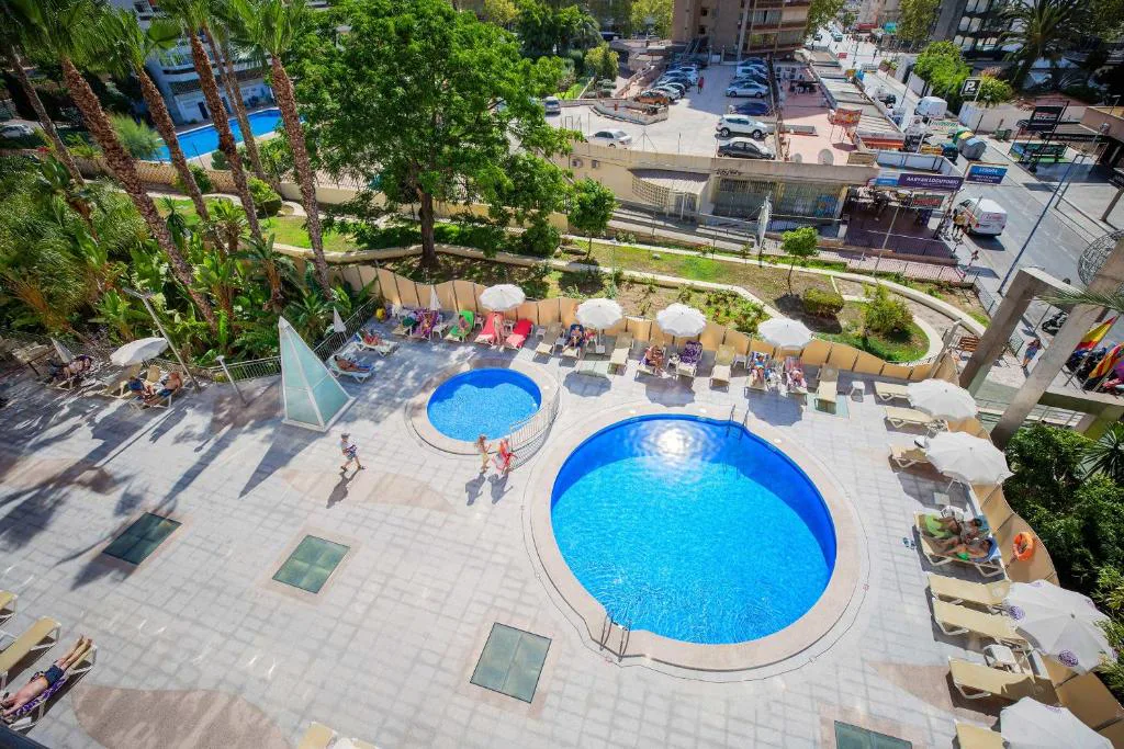 Piscina exterior con tumbonas y hotel al fondo