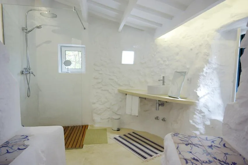Baño de paredes de piedra encalada con ducha acristalada, S'Olivera