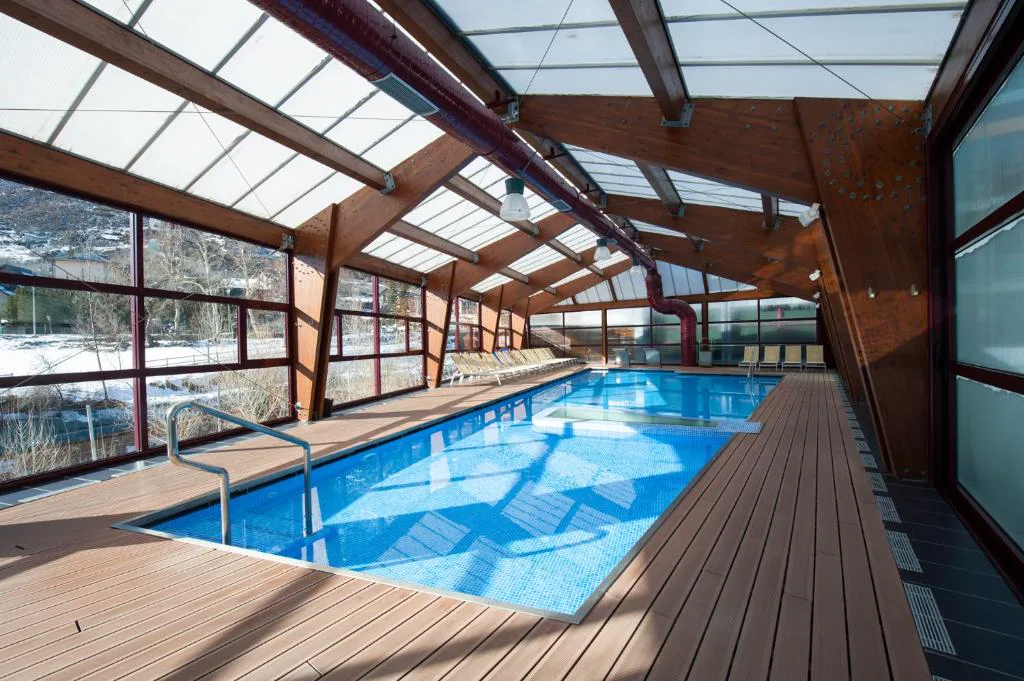 Piscina cubierta con techo de cristal y suelo de madera