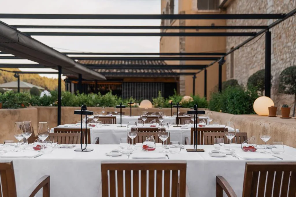 Mesas puestas en la terraza exterior entre olivos por la noche, Son Brull Hotel & Spa