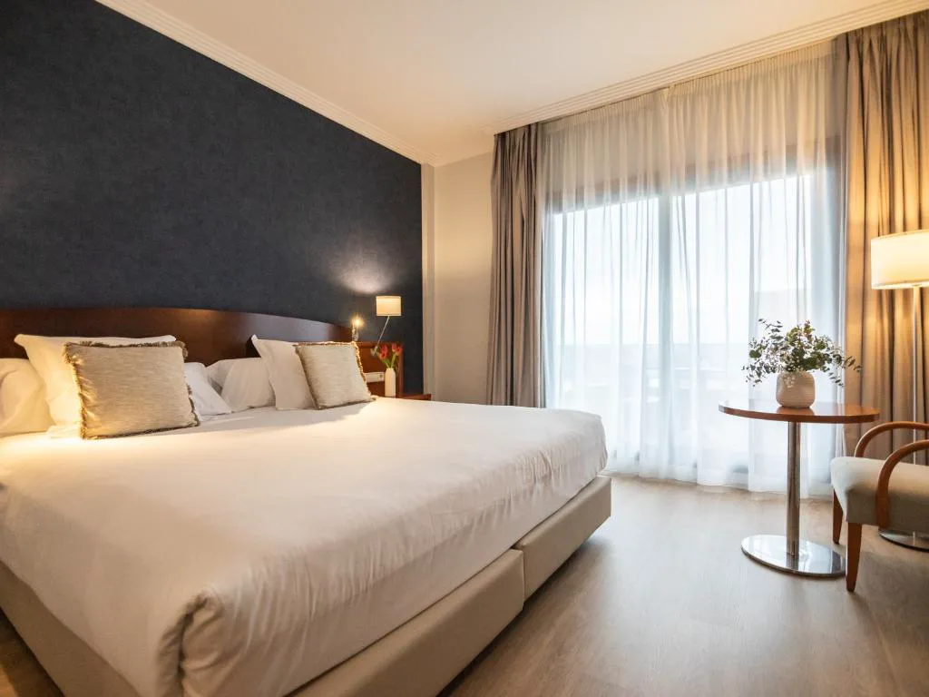 Habitación doble con pared azul marino y balcón con cortinas, Hotel Spa Galatea