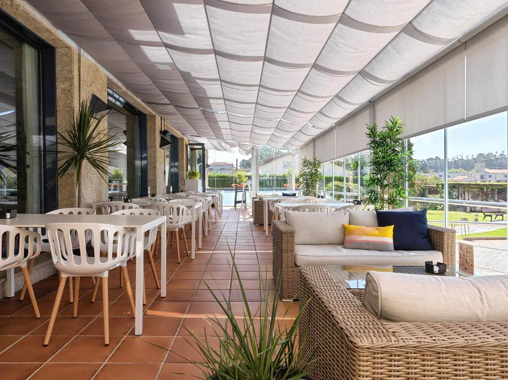 Terraza cubierta con sofás de mimbre y vistas al jardín, Hotel Spa Galatea
