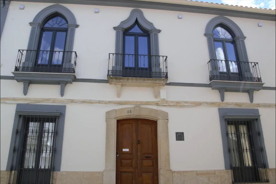 Fachada blanca con balcones y puerta de madera