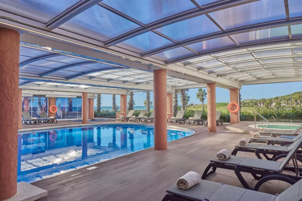 Piscina cubierta con techo acristalado y tumbonas