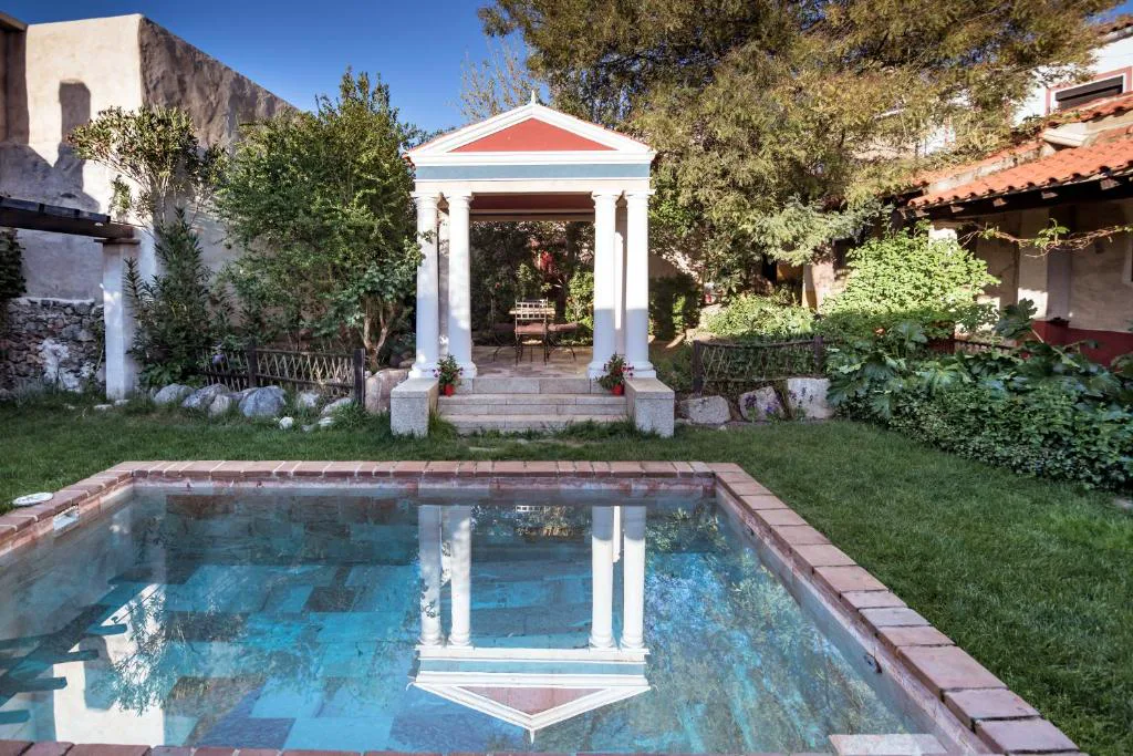 Piscina con un templete de columnas en un jardín