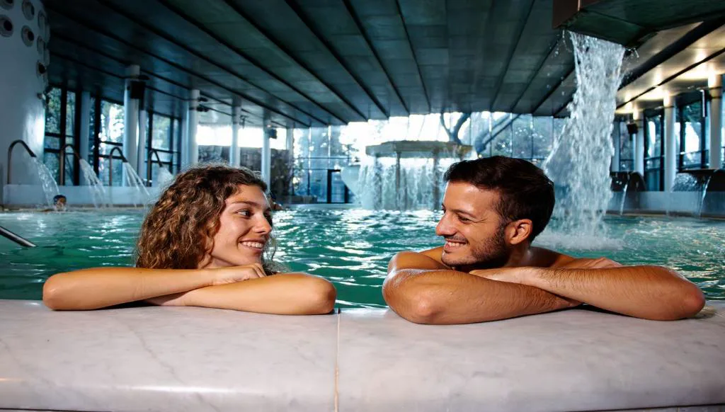 Pareja en la piscina termal bajo una cascada