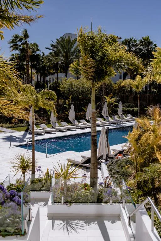 Piscina exterior con vegetación y vista al mar al fondo