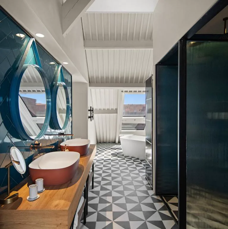 Baño con dos lavabos de diseño, espejos redondos y bañera exenta, The Lince Santa Clara