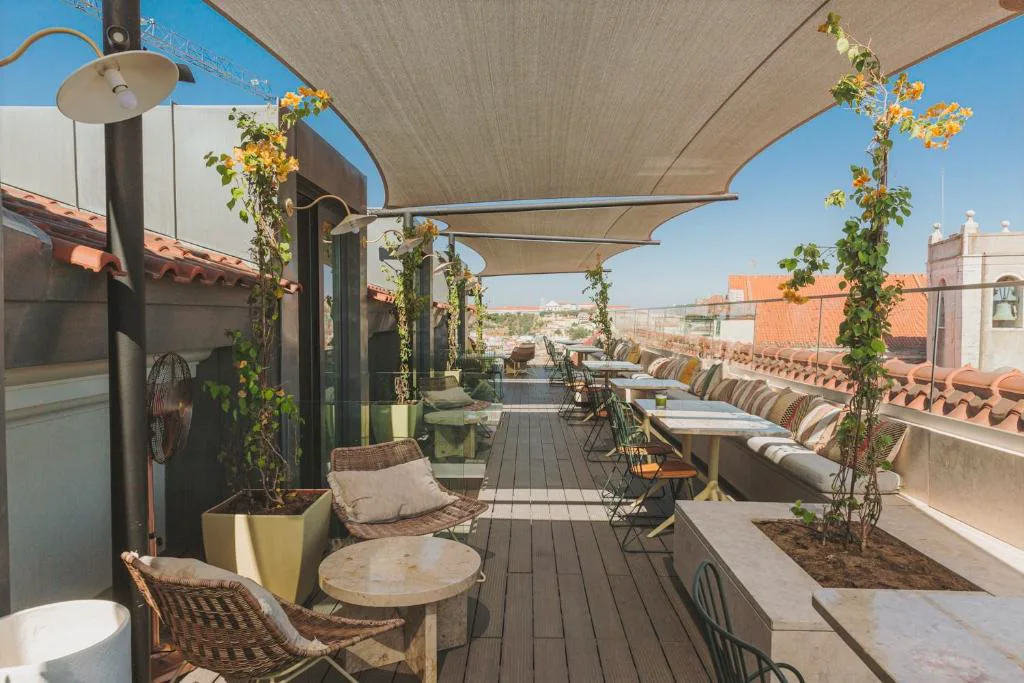 Terraza de la azotea de The Lumiares con toldos y buganvillas, vistas a los tejados de Lisboa