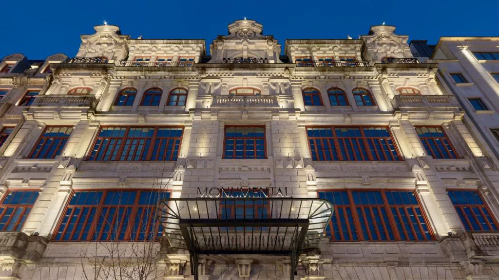 Fachada de 1923 de The One Monumental Palace iluminada de noche, con el rótulo Monumental