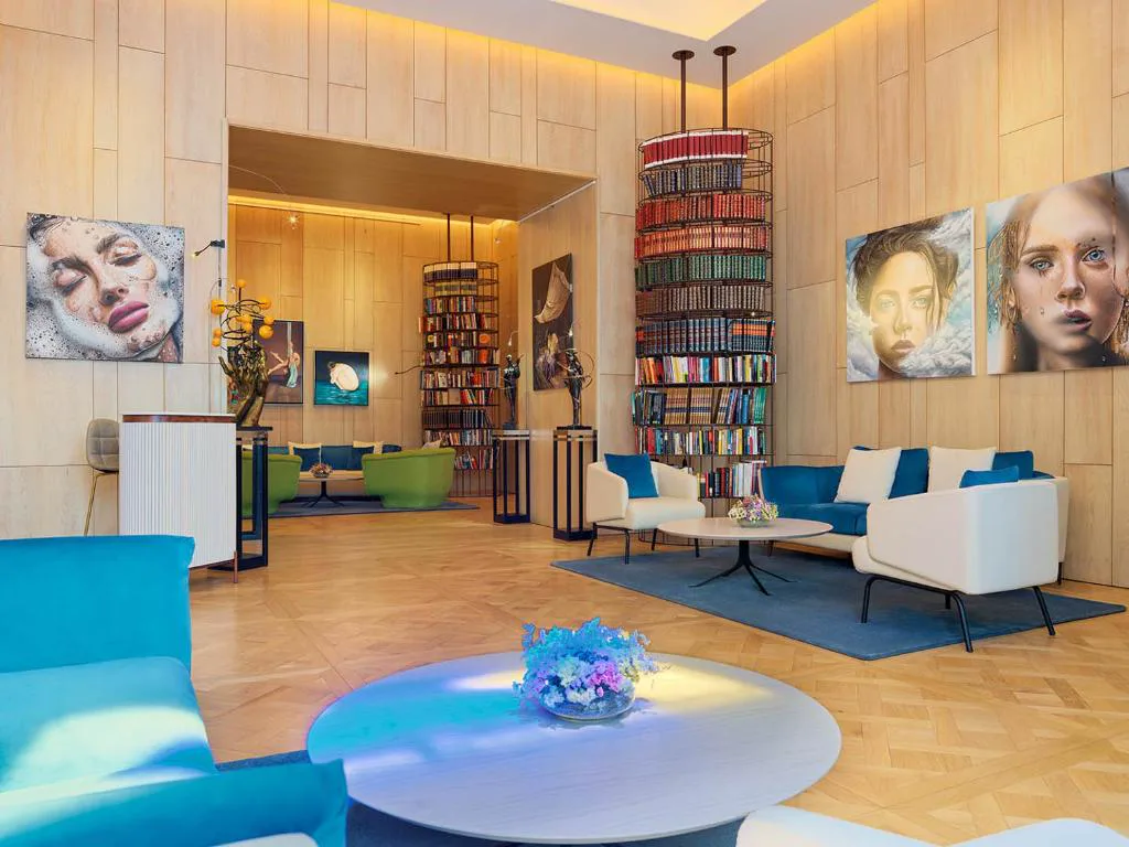Salón lounge con torres de libros y retratos de arte contemporáneo, The One Palácio da Anunciada