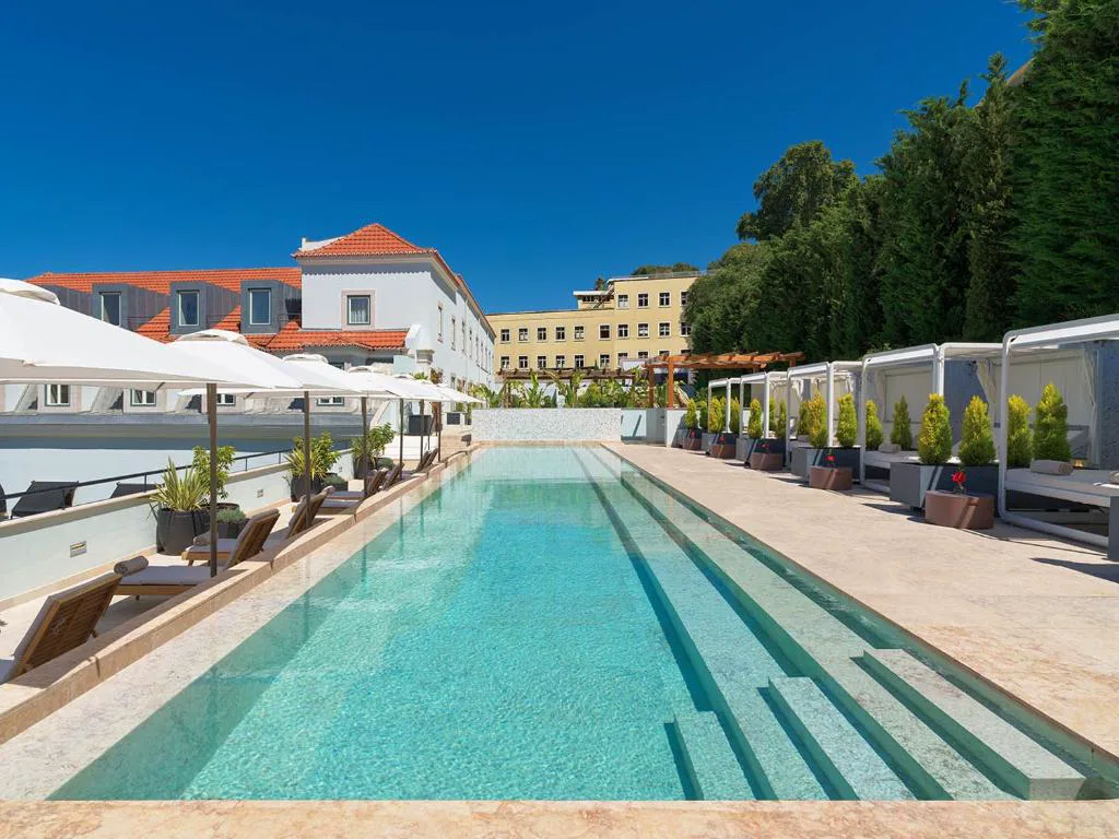 Piscina exterior de día junto al patio ajardinado del palacete
