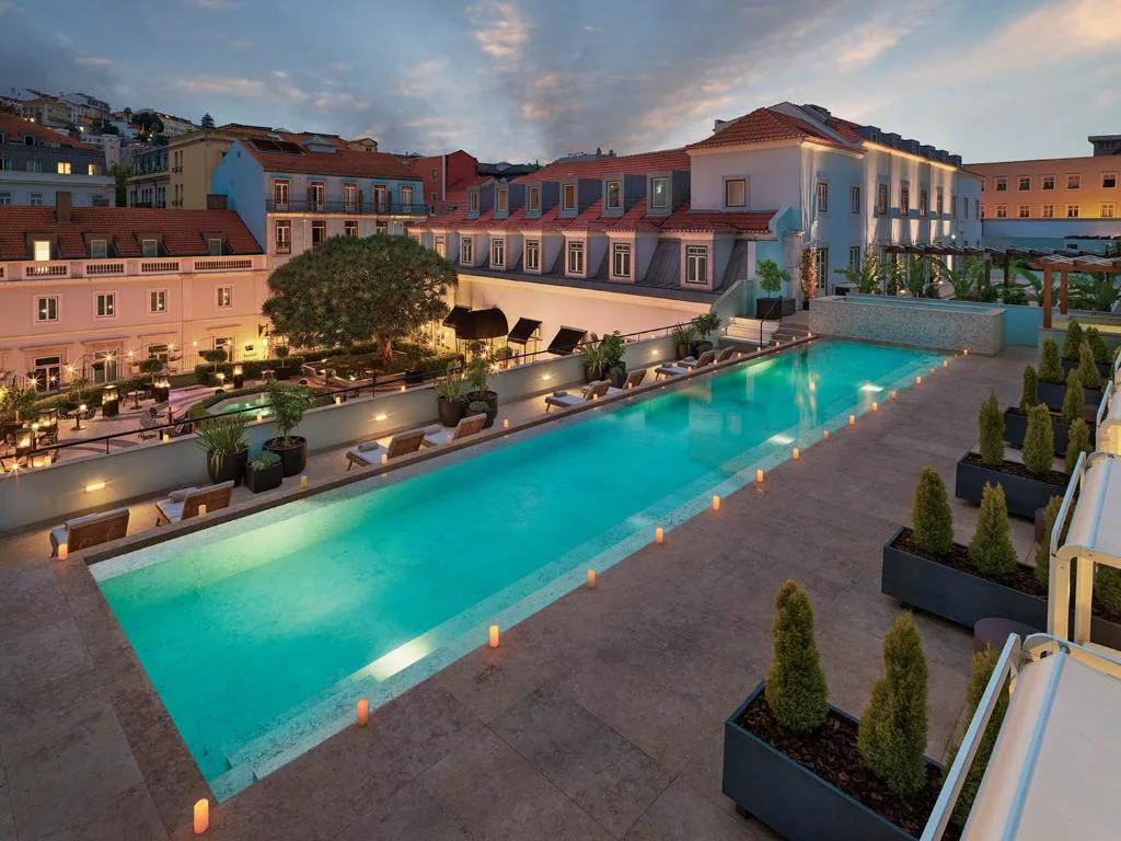 Piscina exterior de The One Palácio da Anunciada iluminada al atardecer, entre las fachadas del palacete, Lisboa