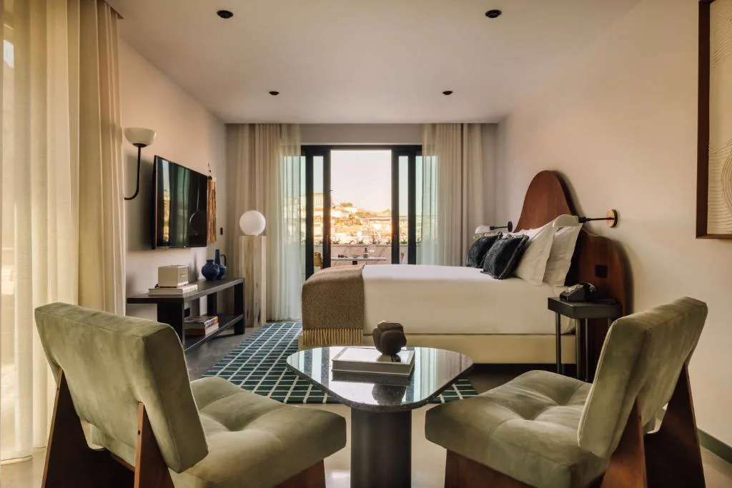 Habitación de The Rebello con sillones verdes y balcón con vistas al Duero