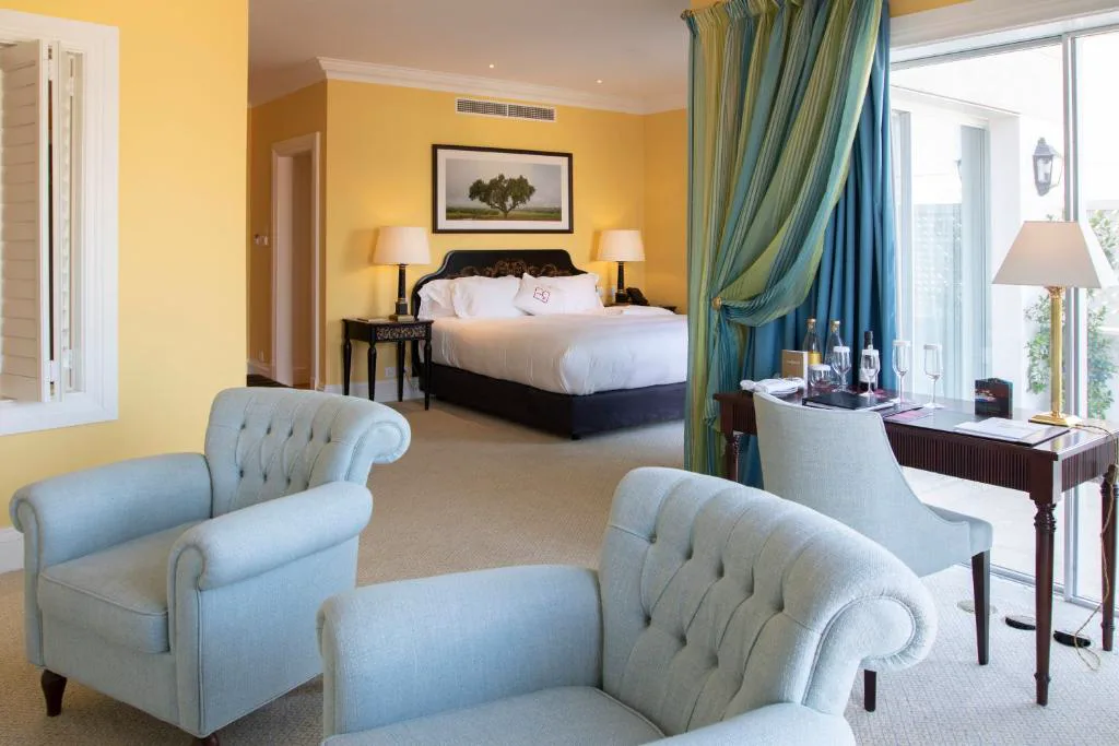 Suite con sofás en azul empolvado, cama y mesa con copas de vino, The Yeatman