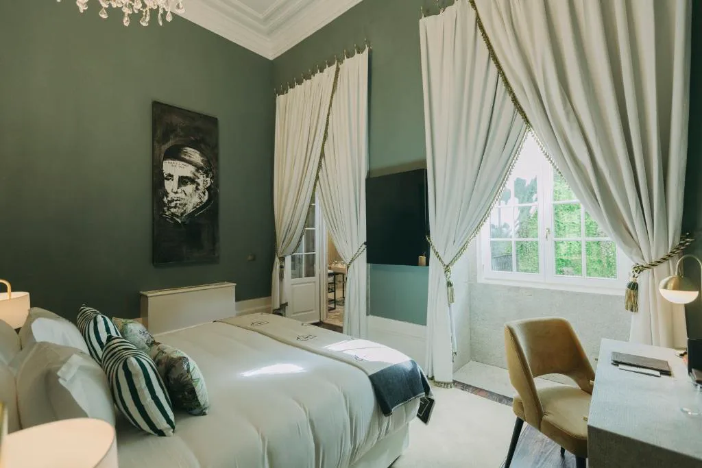 Habitación en verde oscuro con cortinas doradas y retrato en la pared, Torel Palace Porto