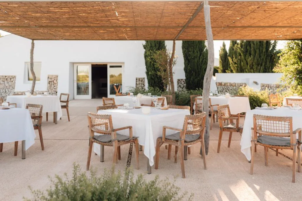 Terraza del restaurante con mesas vestidas de blanco bajo un porche de cañizo, Torralbenc