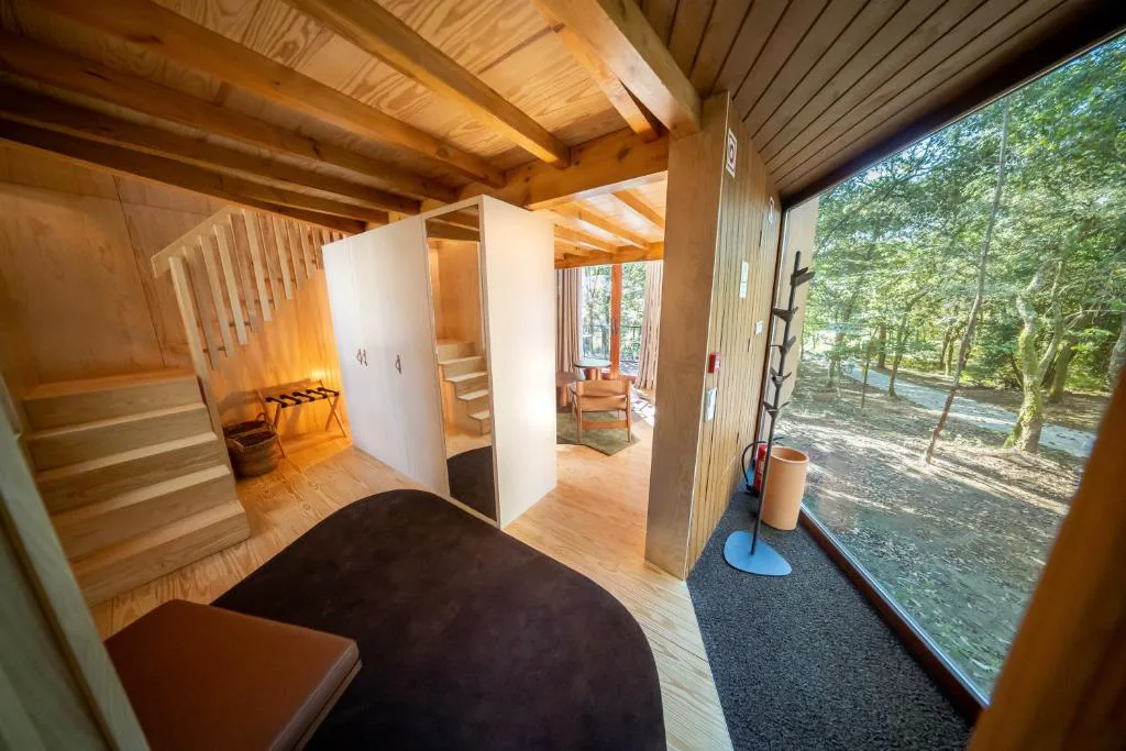 Interior de un bungalow con escalera de madera y vistas al bosque, Torre de Gomariz