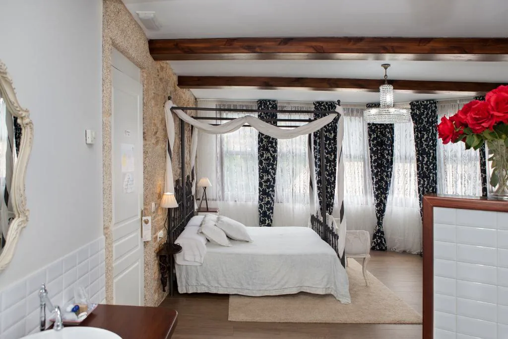 Cama con dosel de hierro forjado, lámpara de araña y rosas rojas, A Torre de Laxe