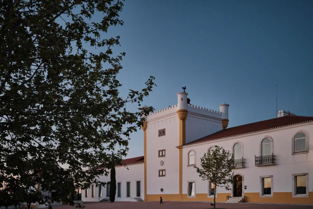 Fachada encalada de Torre de Palma Wine Hotel al atardecer, con su torre almenada