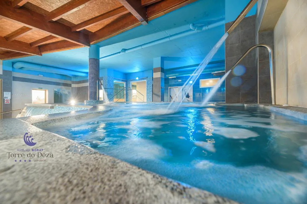 Chorros de hidromasaje bajo vigas de madera junto a columna de mosaico azul, Hotel Spa Norat Torre do Deza