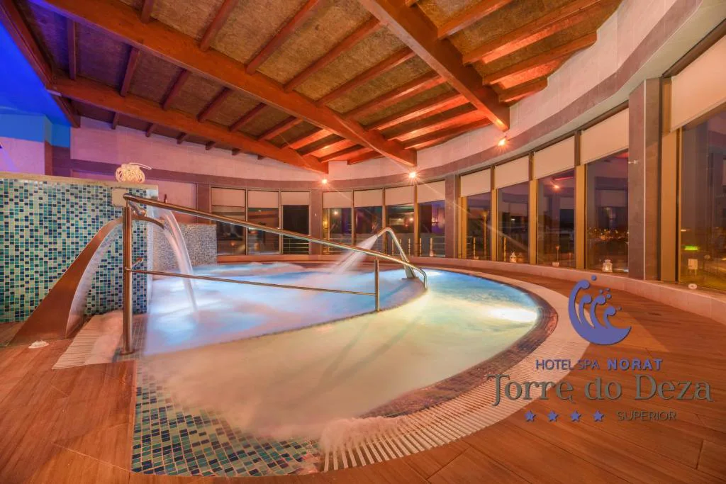 Piscina de hidromasaje circular con cascadas y luz azul al atardecer, Hotel Spa Norat Torre do Deza, Lalín