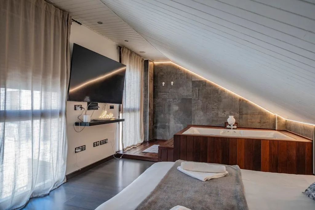 Dormitorio con bañera de hidromasaje y televisión