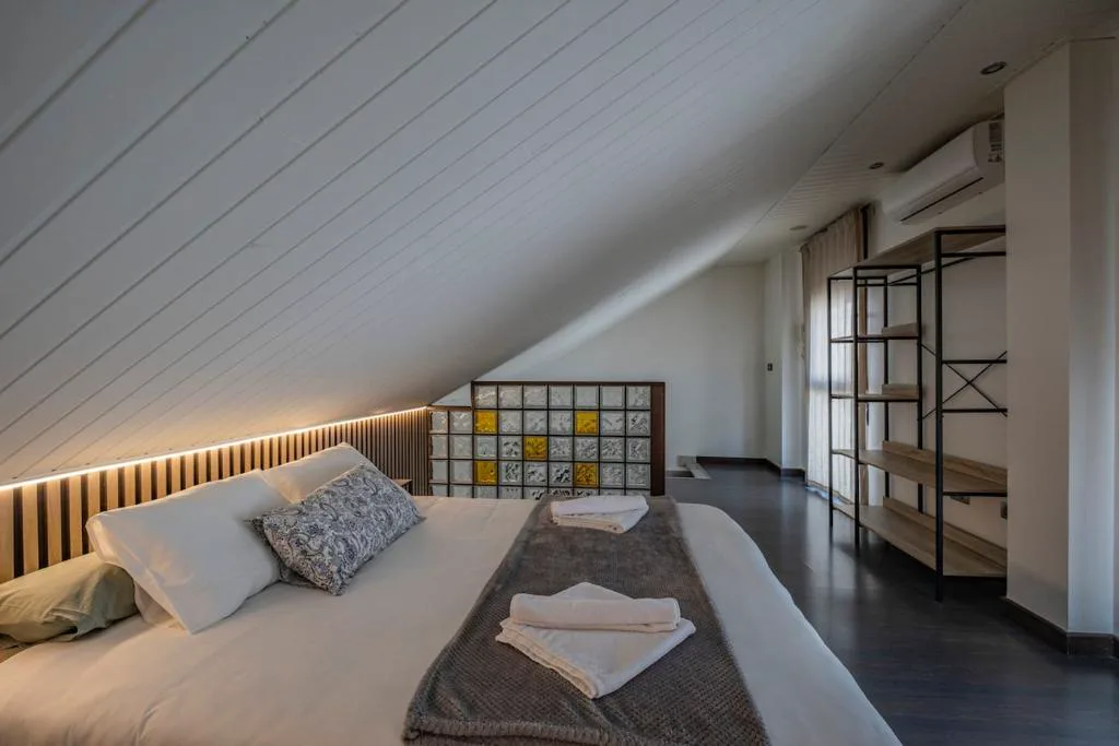 Suite abuhardillada con cama, estanterías y bañera