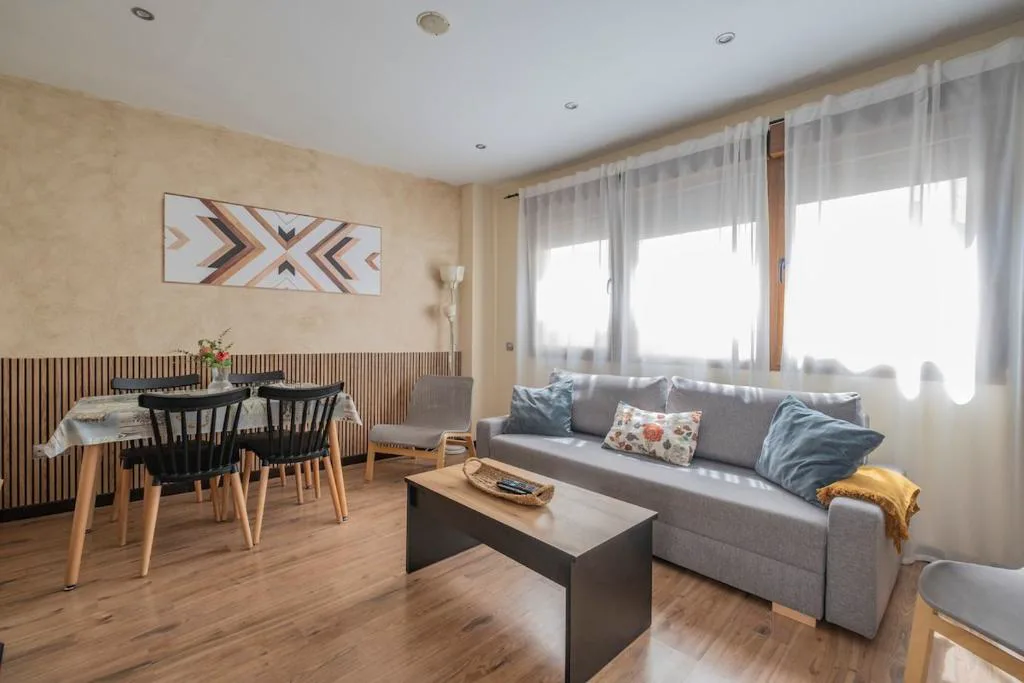 Salón con sofá gris y mesa de comedor de cuatro sillas